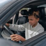 Jongeman die zich voorbereidt op het halen van zijn auto rijbewijs met een instructeur in de auto.
