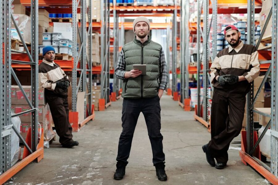Een team logistiek medewerkers die samenwerken in een magazijnomgeving, gericht op efficiëntie en teamwork.